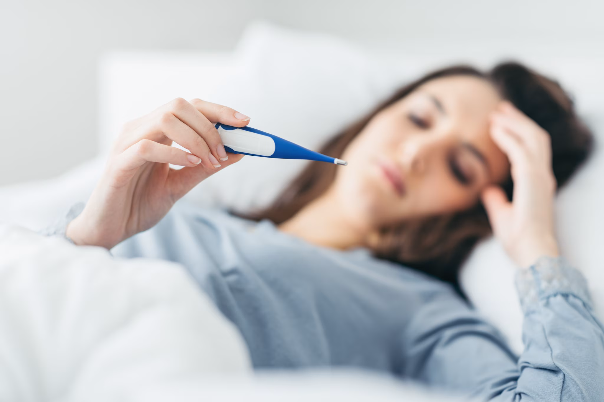 Woman lying in bed reading thermometer