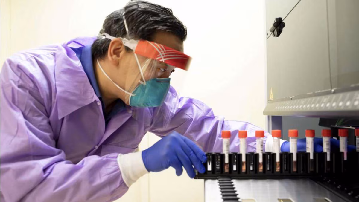 BAA UCSF Man with laboratory safety gear slides vials into a machine.