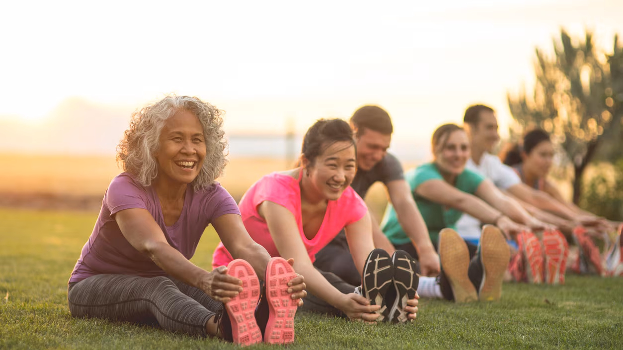 Adults stretching outside and smiling.