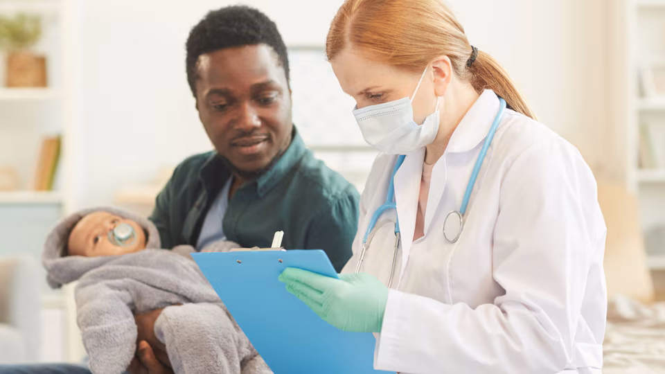 Father and newborn at the doctor Father holding his newborn while talking to a healthcare provider.