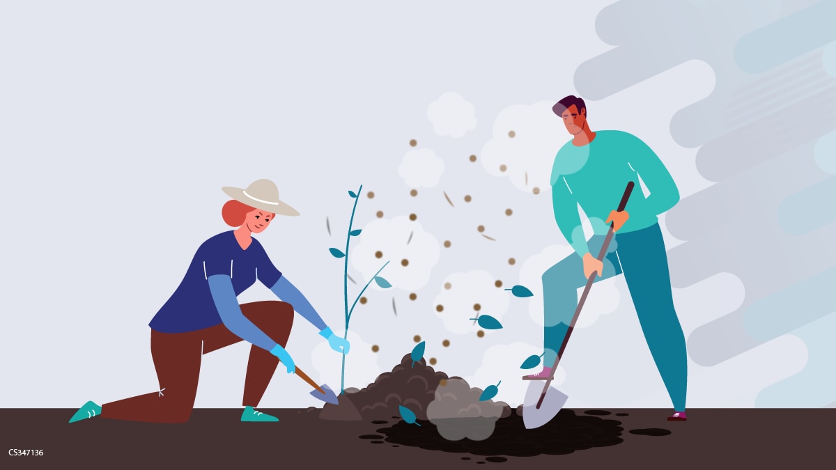 People gardening woman and man digging around a tree. They are wearing long sleeves and pants and gloves
