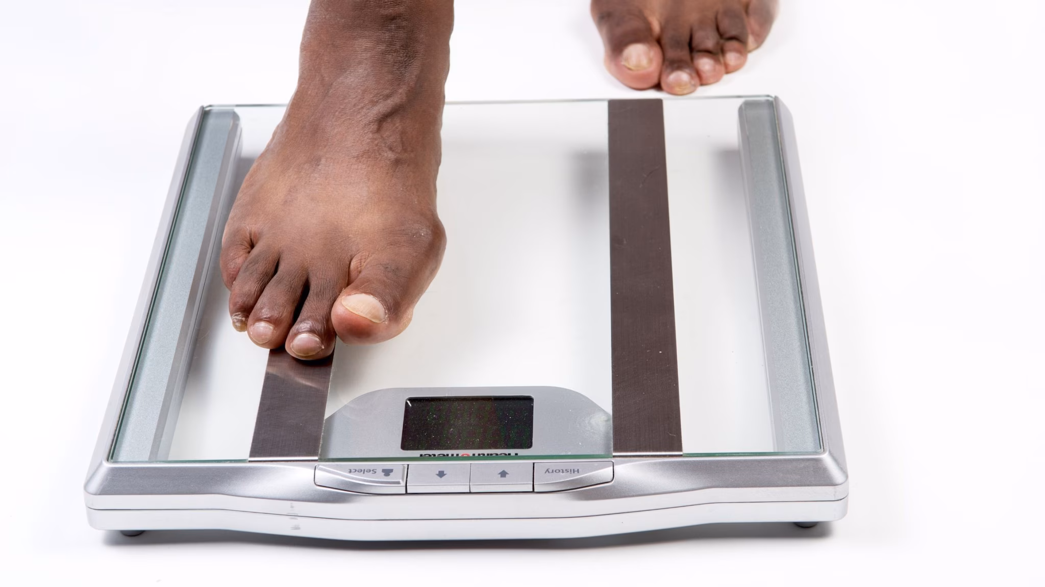 A person's feet stepping on electronic scales.