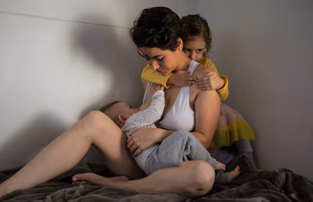 Mother breastfeeding her infant and comforting her older child during an emergency.