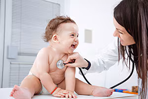 Laughing baby examined by female doctor.