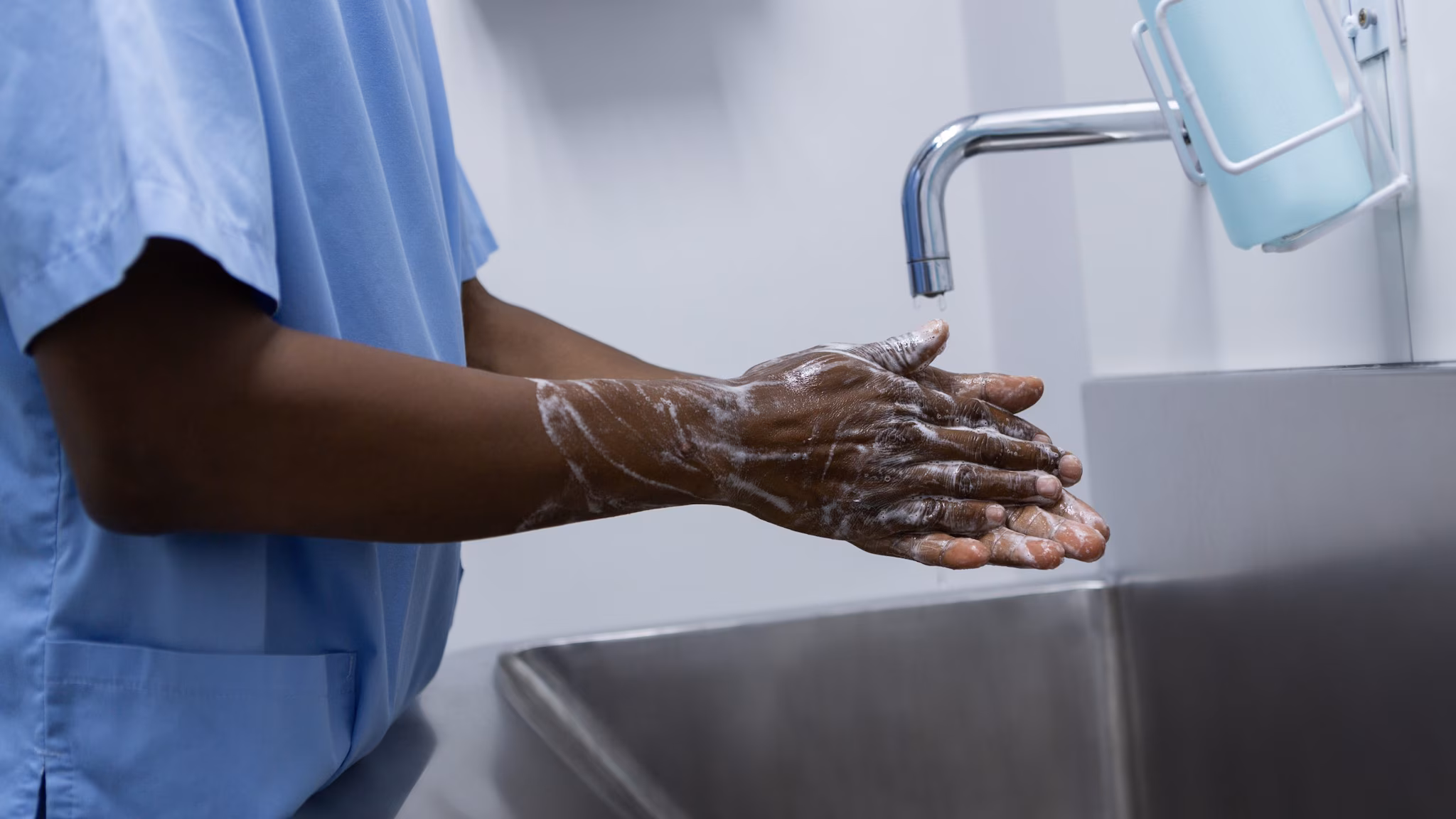 Healthcare provider washing his hands with soap and water.