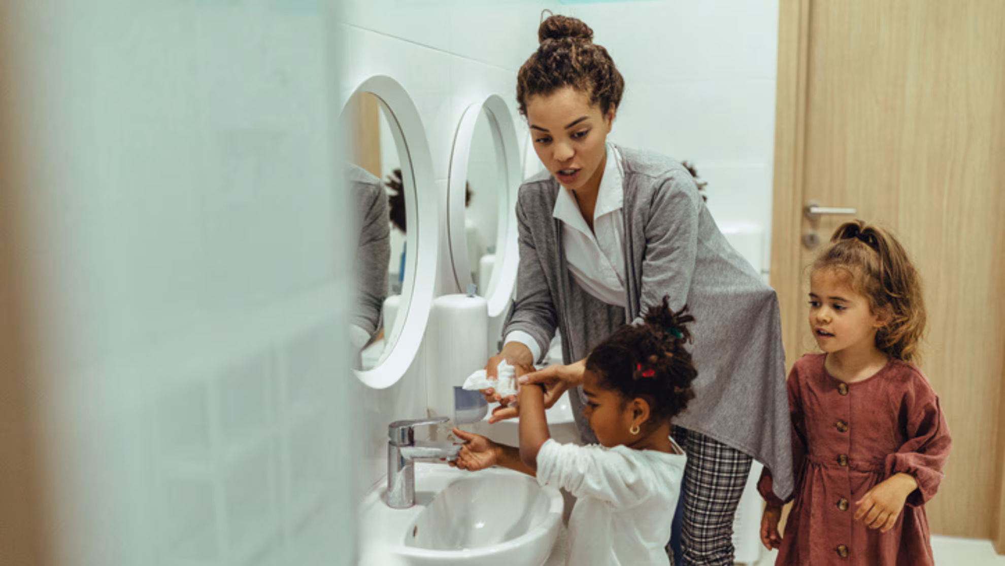 teacher helping child wash their hands