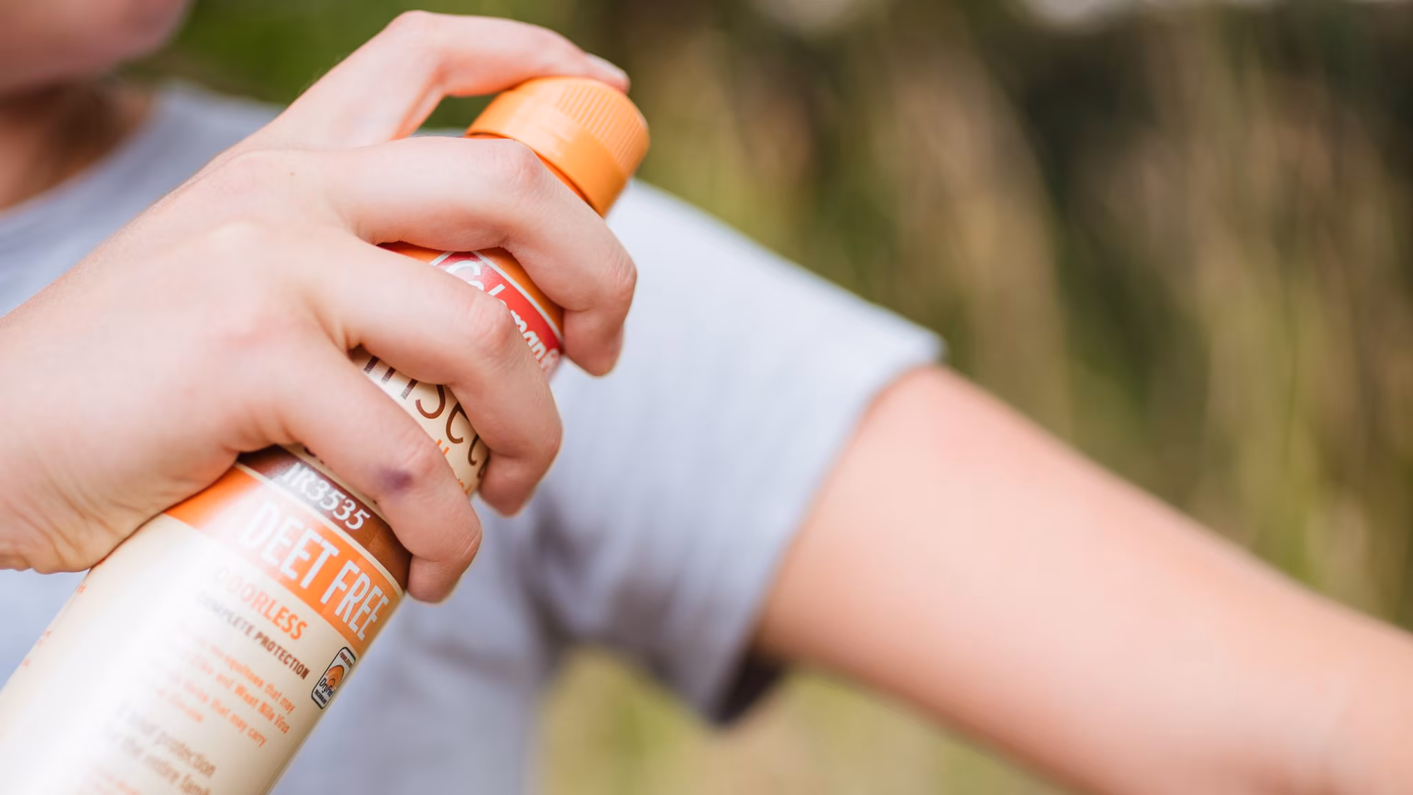 Woman spraying herself with insect repellent
