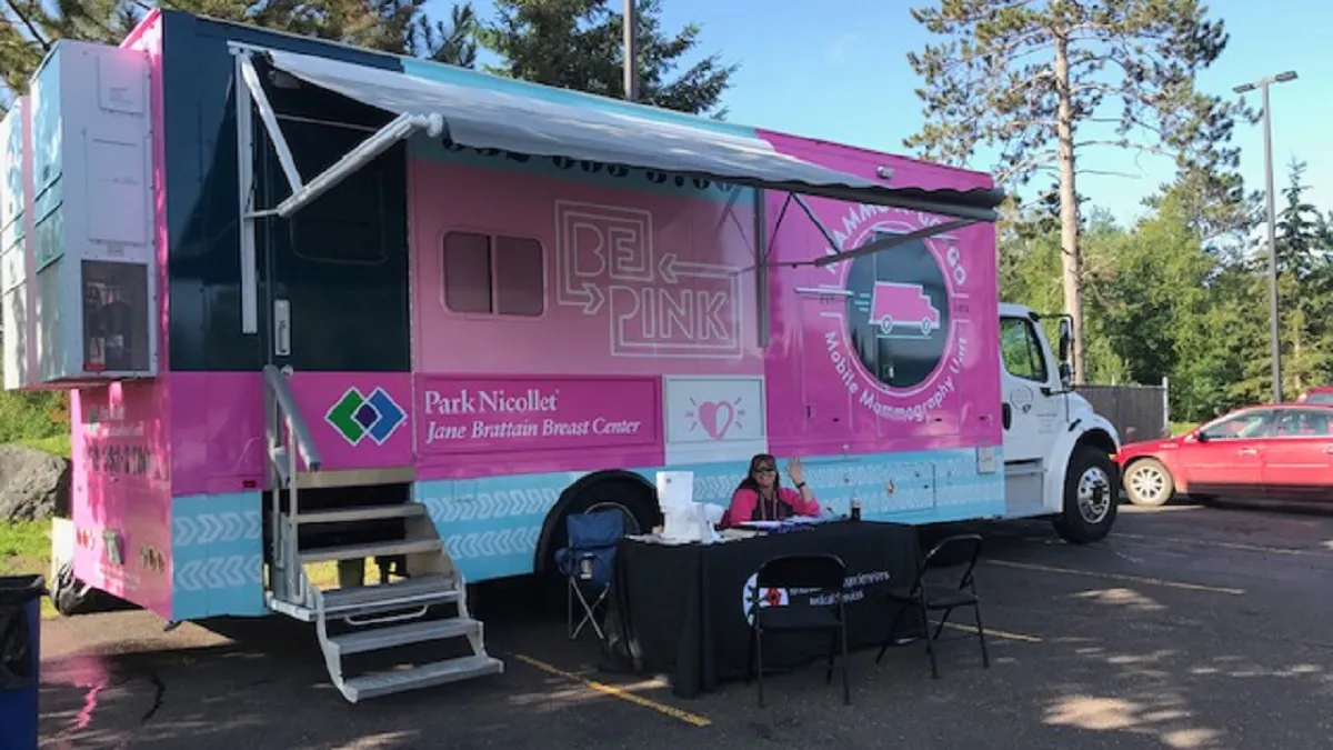 Park Nicollet mammobus a health care worker in front of a Park Nicollet Mobile Mammography Unit