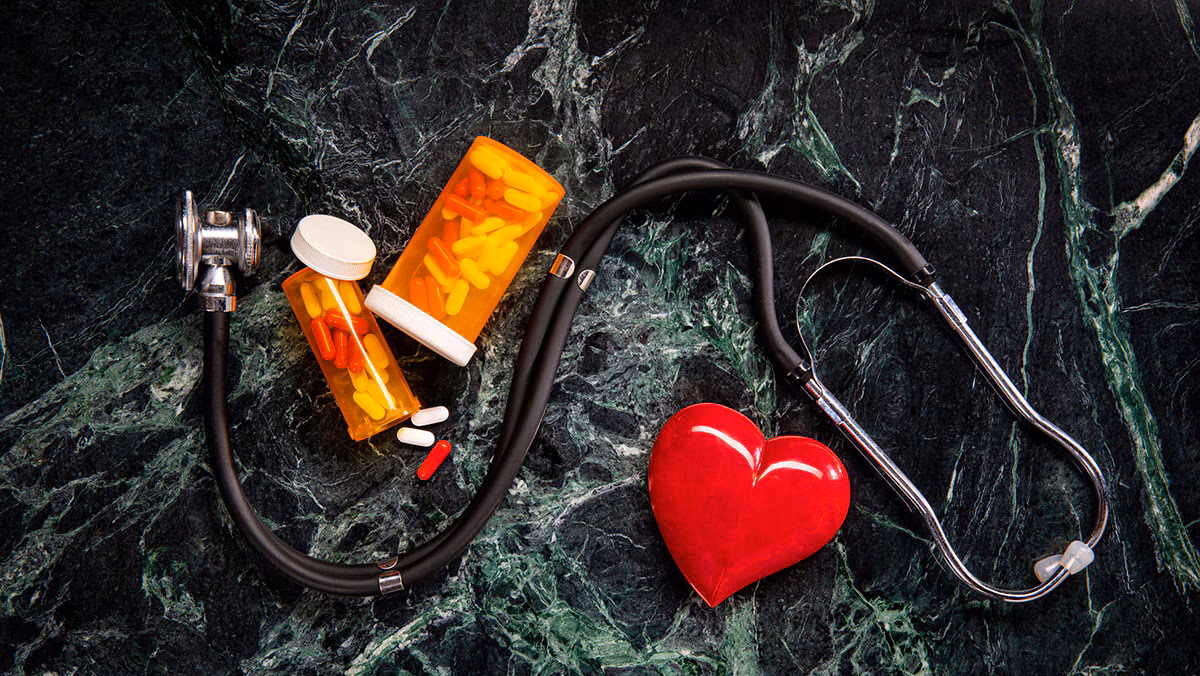 medicine and stethoscope on green marble background