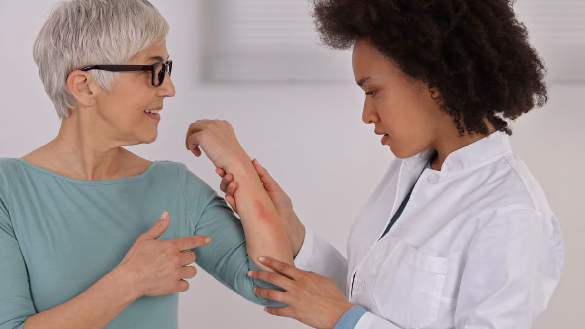 An older woman with a rash on her arm is examined by a dermatologist.