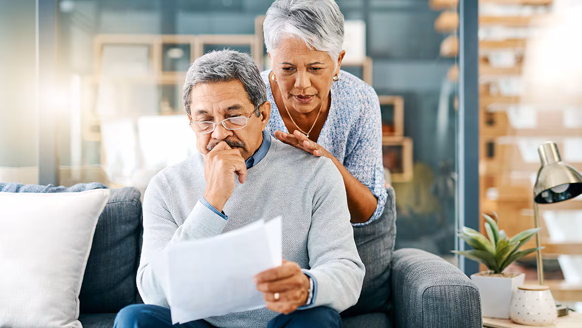 There can be burdens to budgeting mature couple looking worried while going through paperwork together at home
