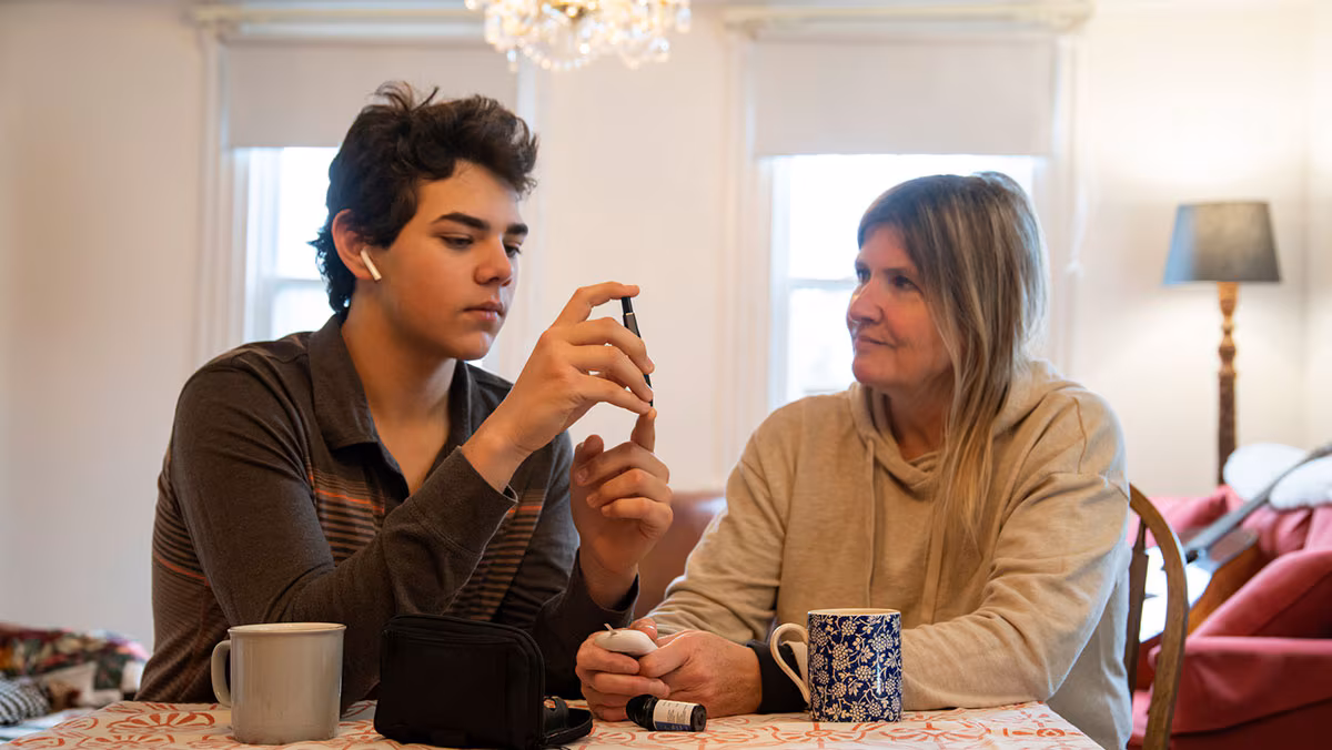A diabetic teen patient at home with his mother. A diabetic teen patient at home with his mother.