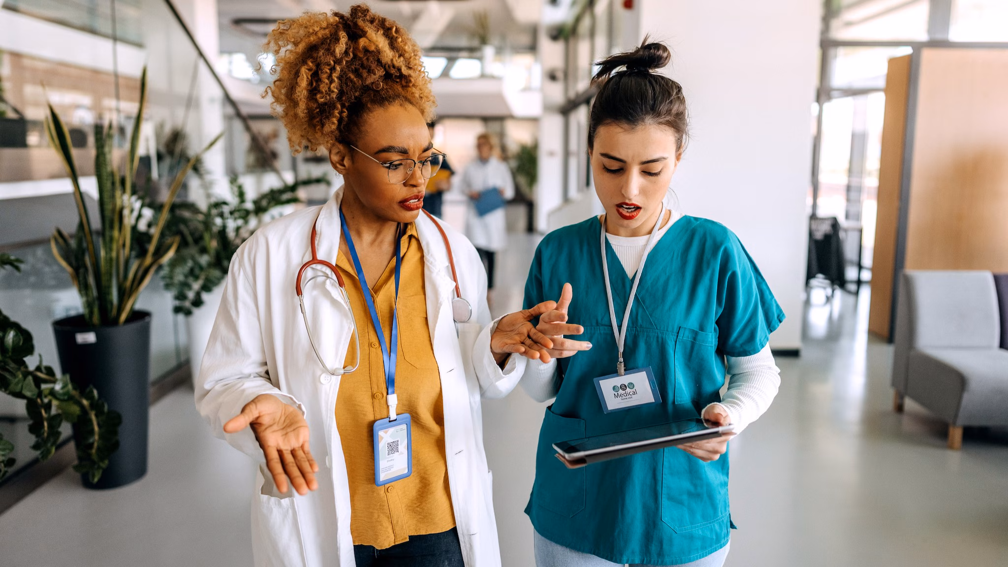 Two clinicians discussing something on their tablet.