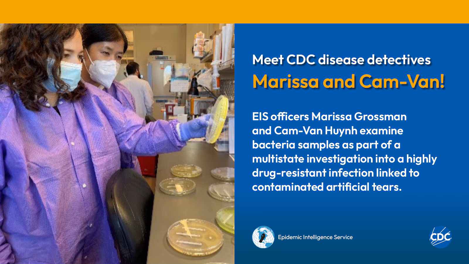 Two woman wearing personal protective equipment while examining laboratory specimens.