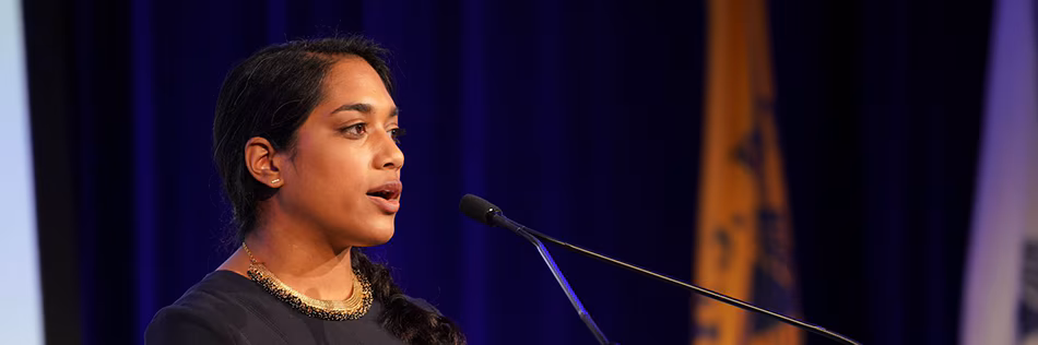 eis-virtual-conference-web-banner-2023-960px Lady standing on stage in front of microphone.