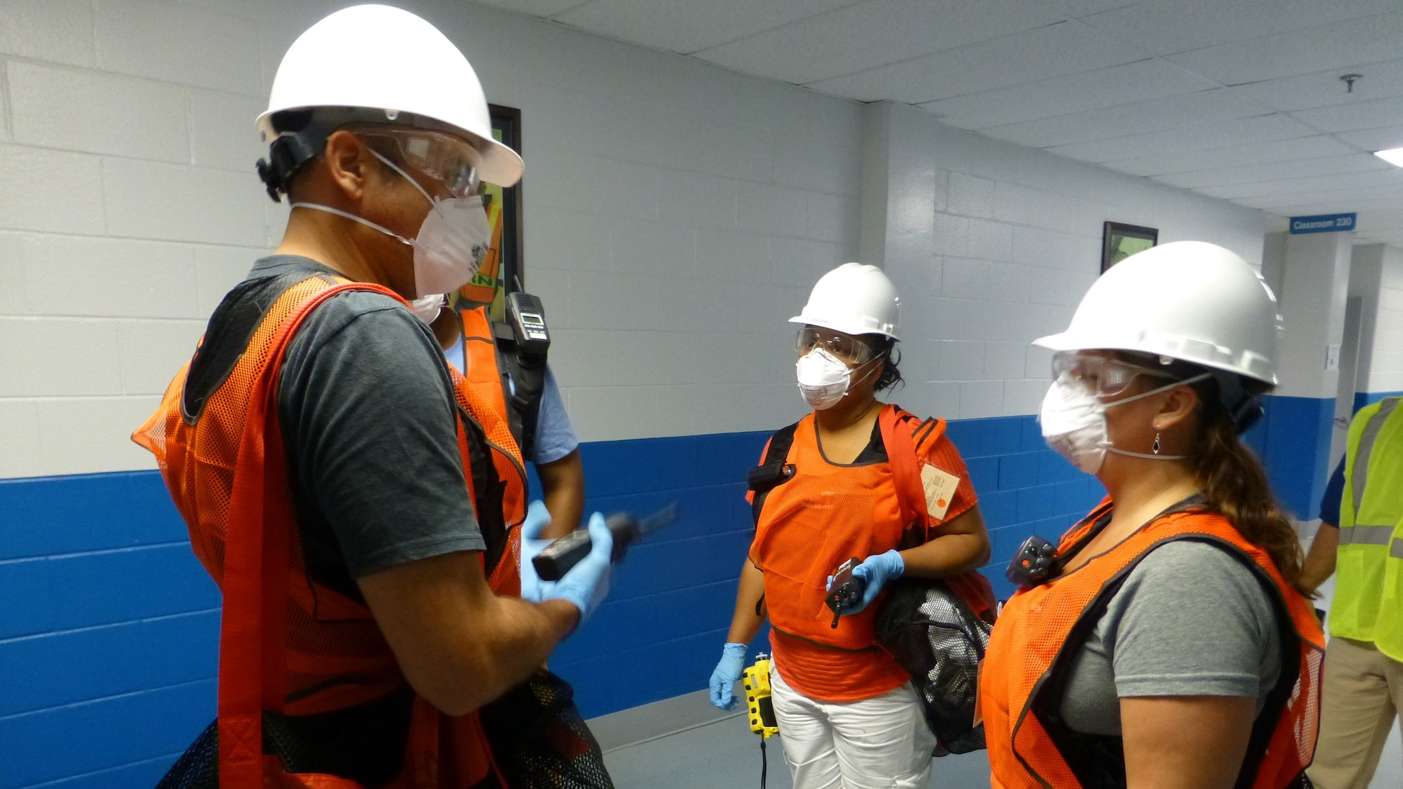Conducting assessments A group of people in hard hats and neon vests inside a building.