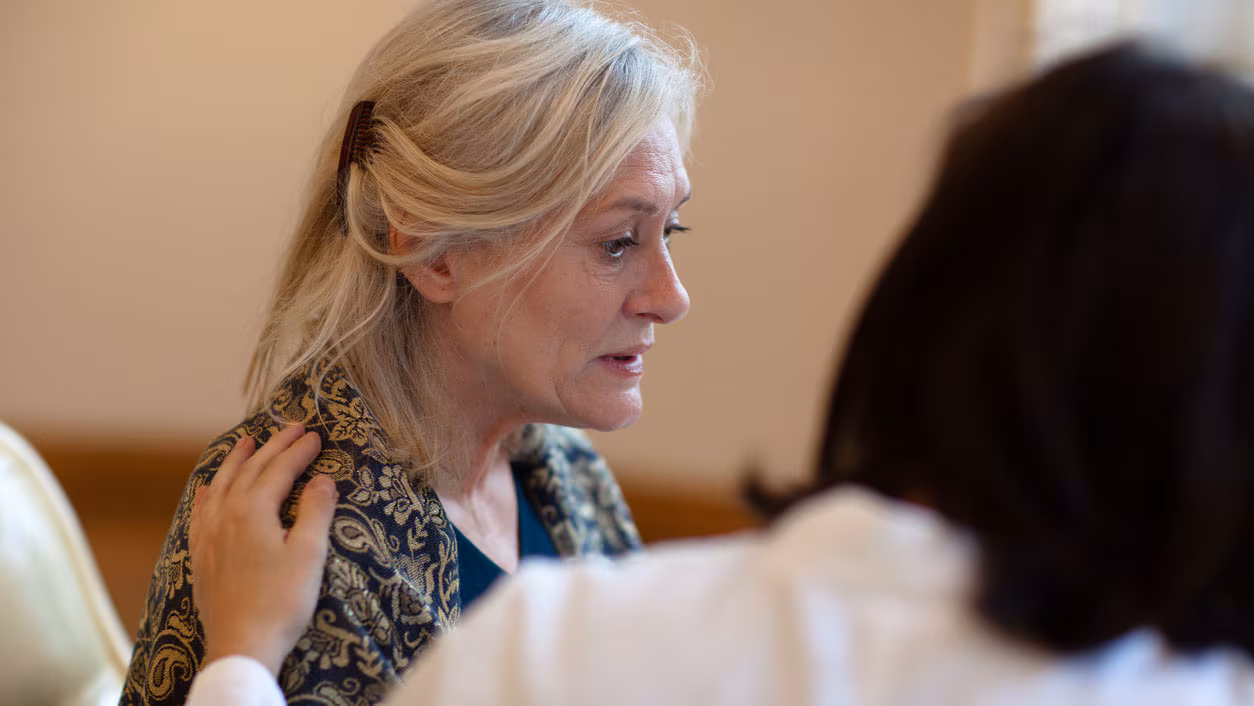 A woman sitting next to caregiver with hand on shoulder A woman sitting next to caregiver with hand on shoulder