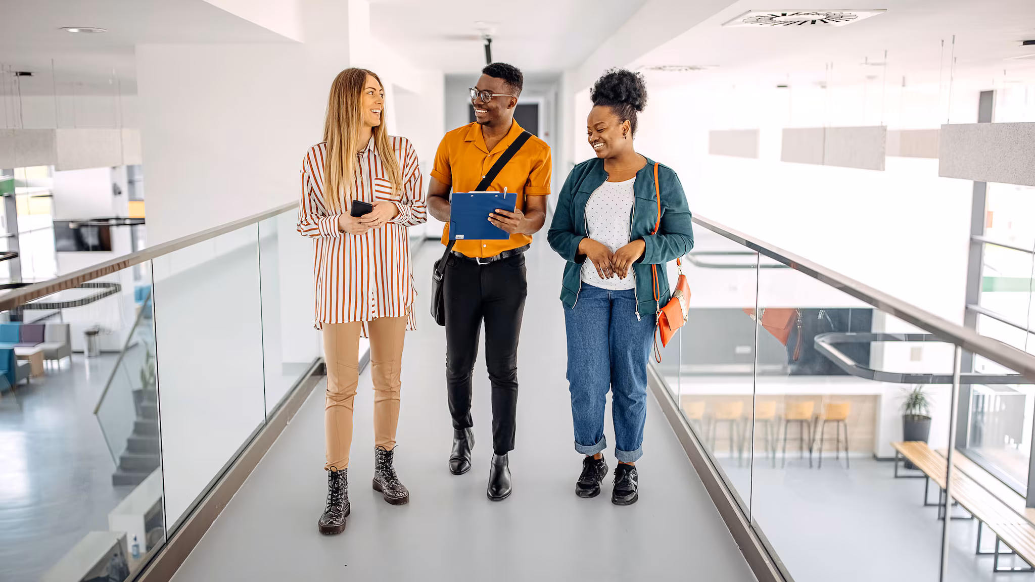 Young trainees walking in office hallway and discussing ideas