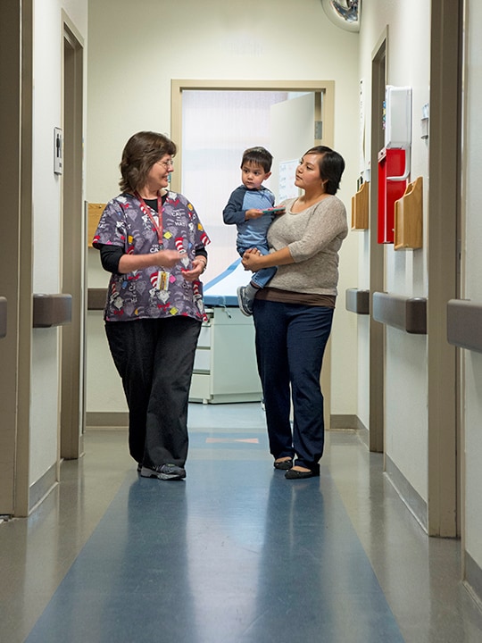 statistic-reporting-AI-AN Nurse talking to an American Indian female patient holding her son in her harms.