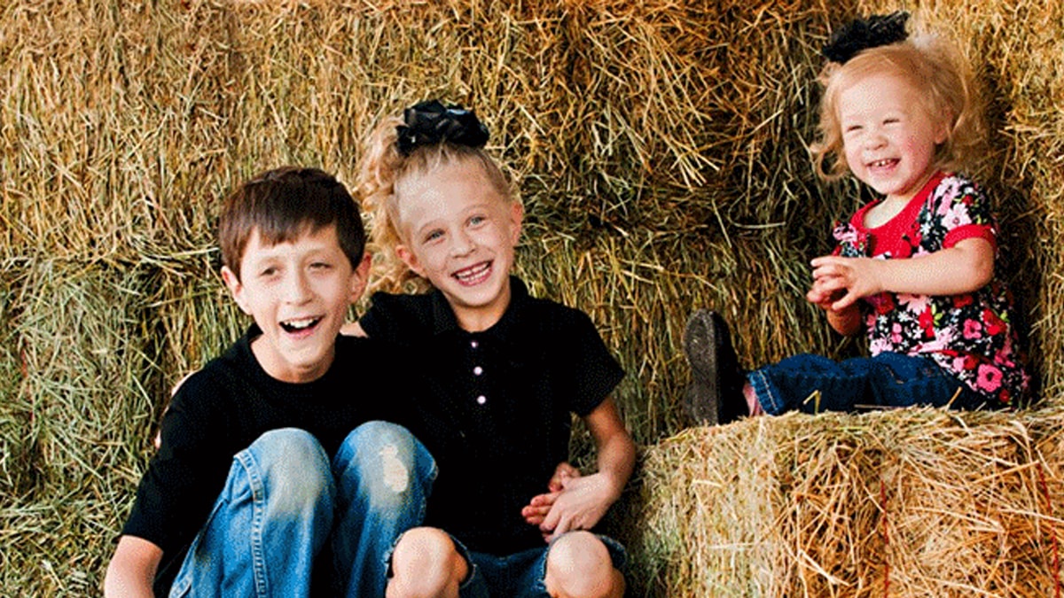 three kids with fxs sitting on haystack three kids with fxs sitting on haystack