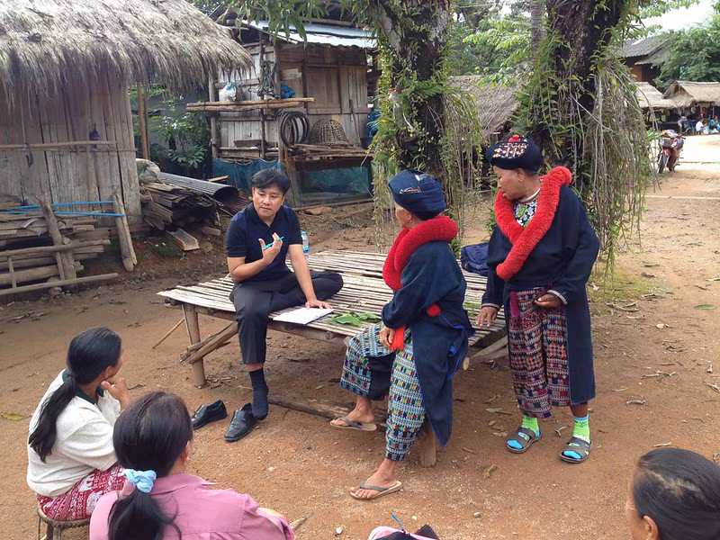 Principle image A male health professional speaking with community members outside in rural Thailand.
