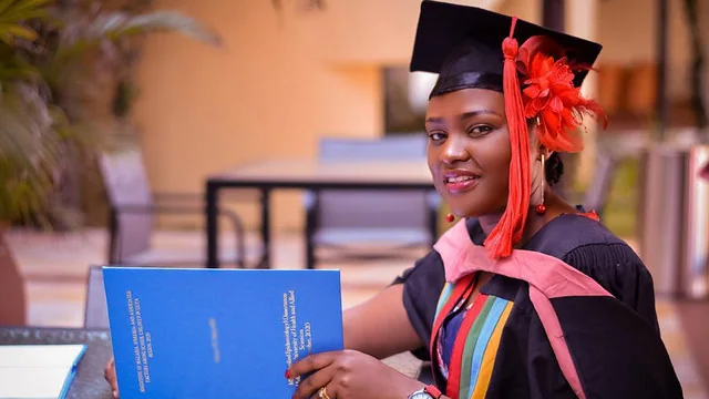Programs-Workforce Woman with graduation attire sitting at a table with a book open.