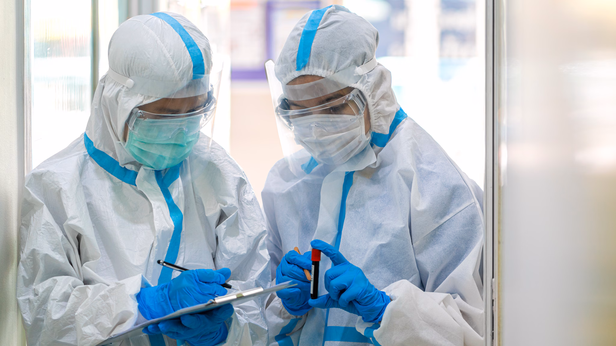 what-we-do-main two people in a lab wearing ppe holding tubes of blood