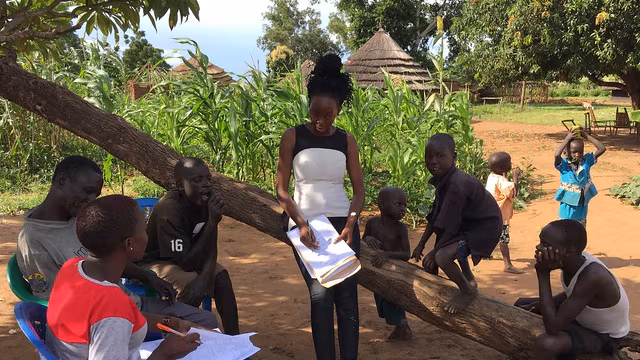 Workforce-core 4 list-second Group of men, woman and children in a field standing in the dirt.