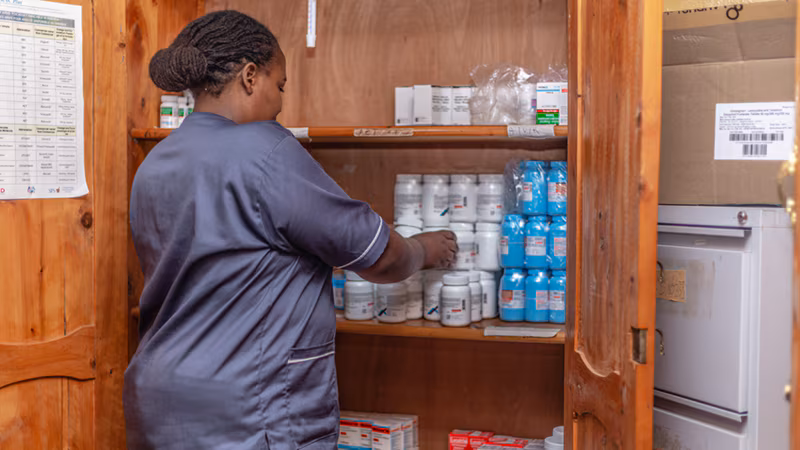 Pursuing_Health_Equity_for_MSM_in_Rwanda Woman checking medication dispensers at a clinic.