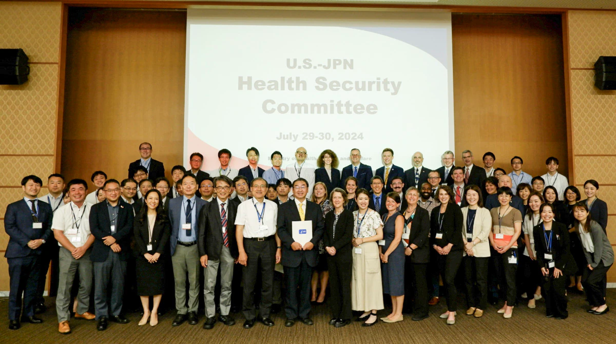 U.S.-Japan Health Security Committee Group of meeting attendees in front of a sign that reads "US.-J Health Security Committee"