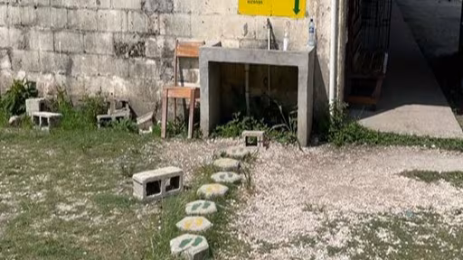 Stepping stones are painted with green and yellow pairs of feet and lead up to a handwashing station.