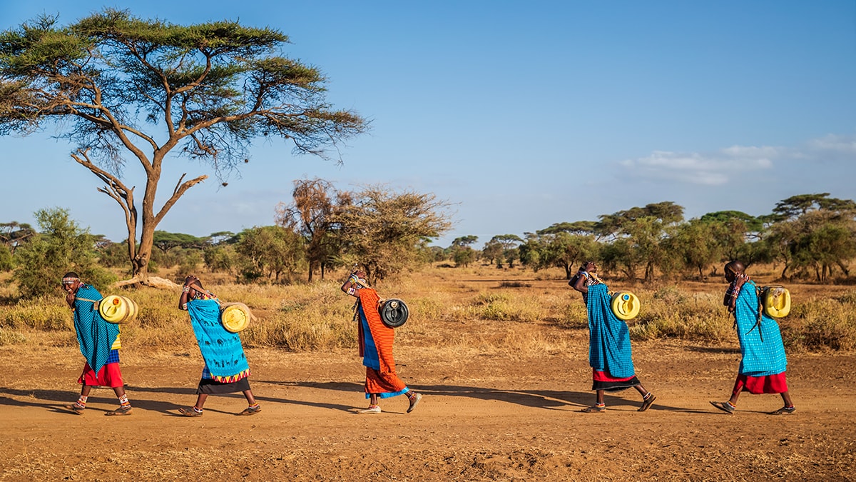 Images_GlobalHealth_1200x675 Global Health Observances - people wearing colorful patterned clothing walk barefoot across a dirt road.