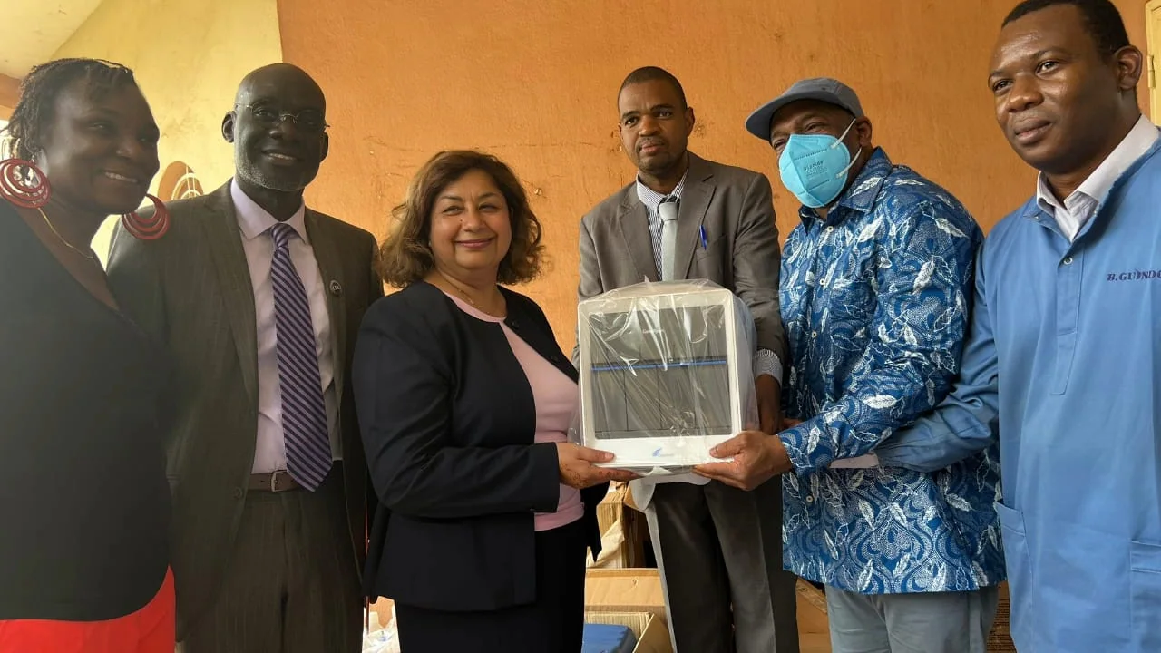 Six individuals pose for a photo while holding a piece of laboratory equipment.