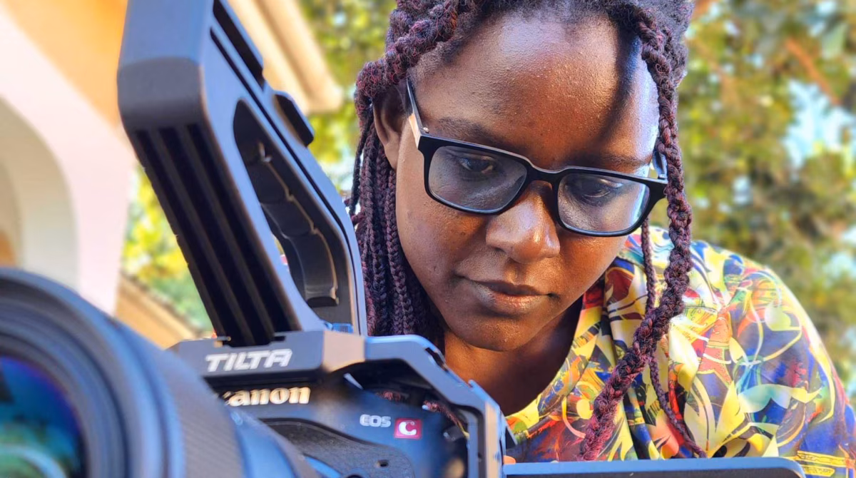 Woman wearing glasses managing a video camera.