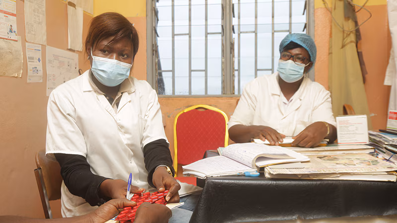 Two health care workers provide HIV treatment pills