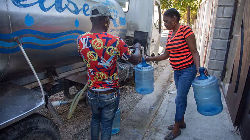 A worker fills water containers from a mobile tanker that provides clean drinking water to families in Haiti’s capital.