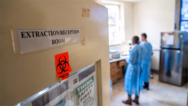 two people in the lab. Sign on door reads Extraction/Reception Room