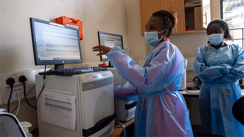 woman wearing mask and protective covering looking at a computer screen