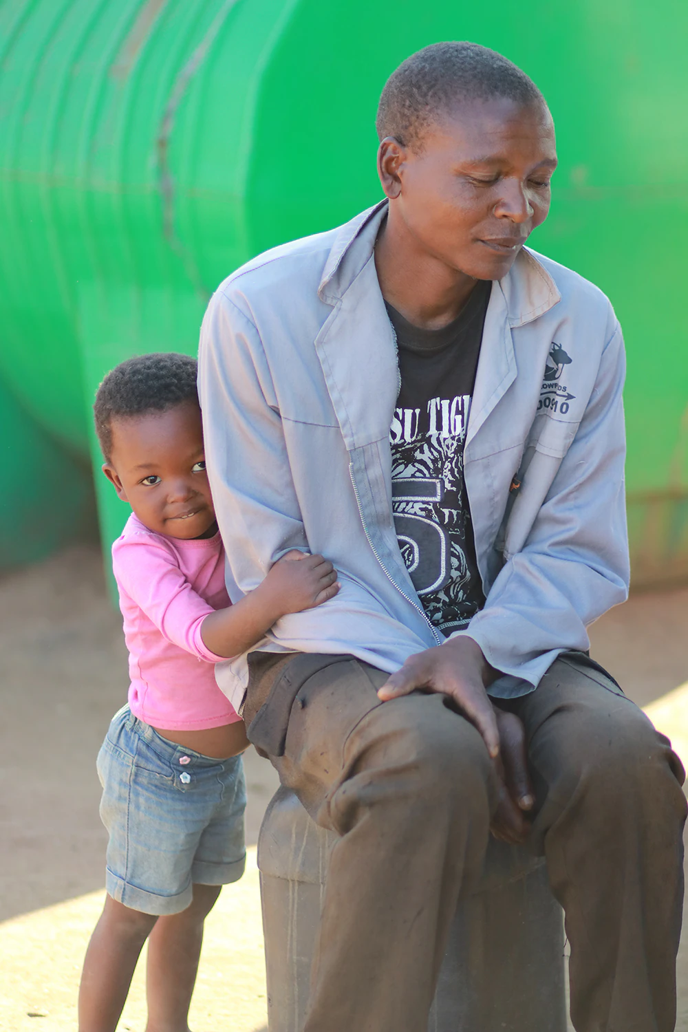 A man in a blue shirt is sitting with his daughter.