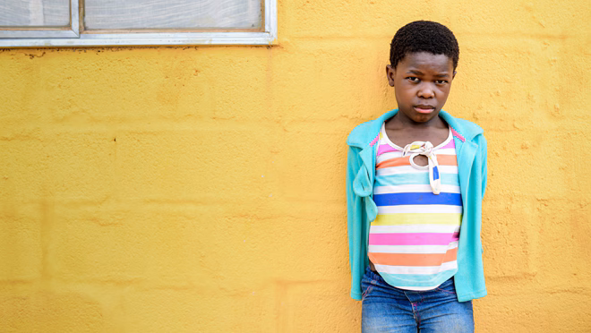 11-year-old Gugu alive and healthy standing in front of a yellow wall