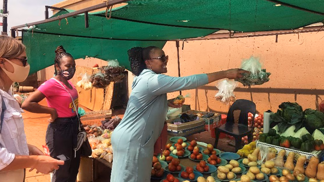 Public health workers in front of program participant's vegetable stand.
