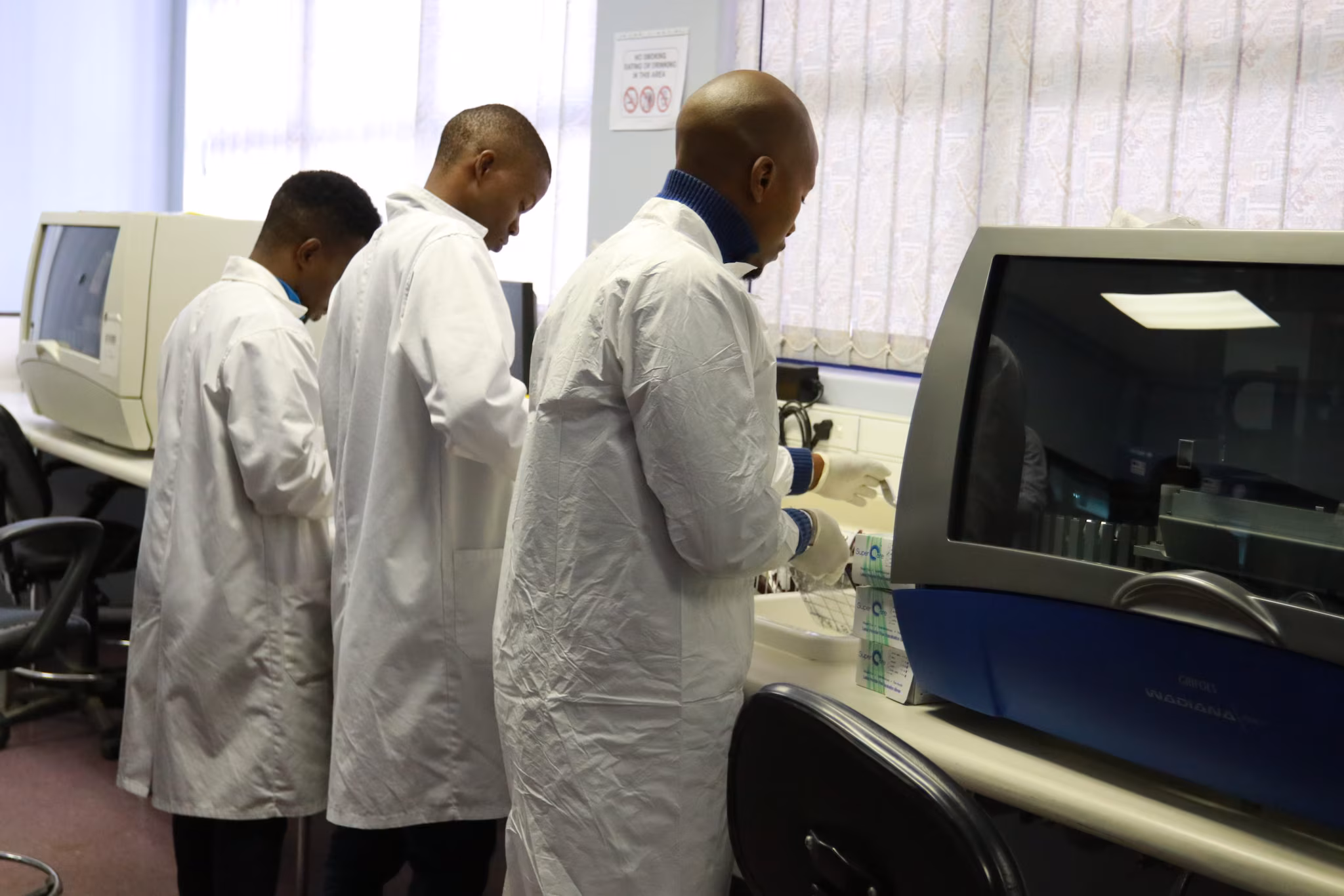 Laboratorians stand side-by-side processing blood donations.