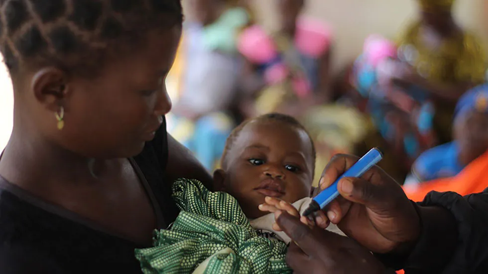 Infant in Mozambique getting finger marked for polio vaccine A mother holds her child, whose finger is being marked to show that the child received a polio vaccine.