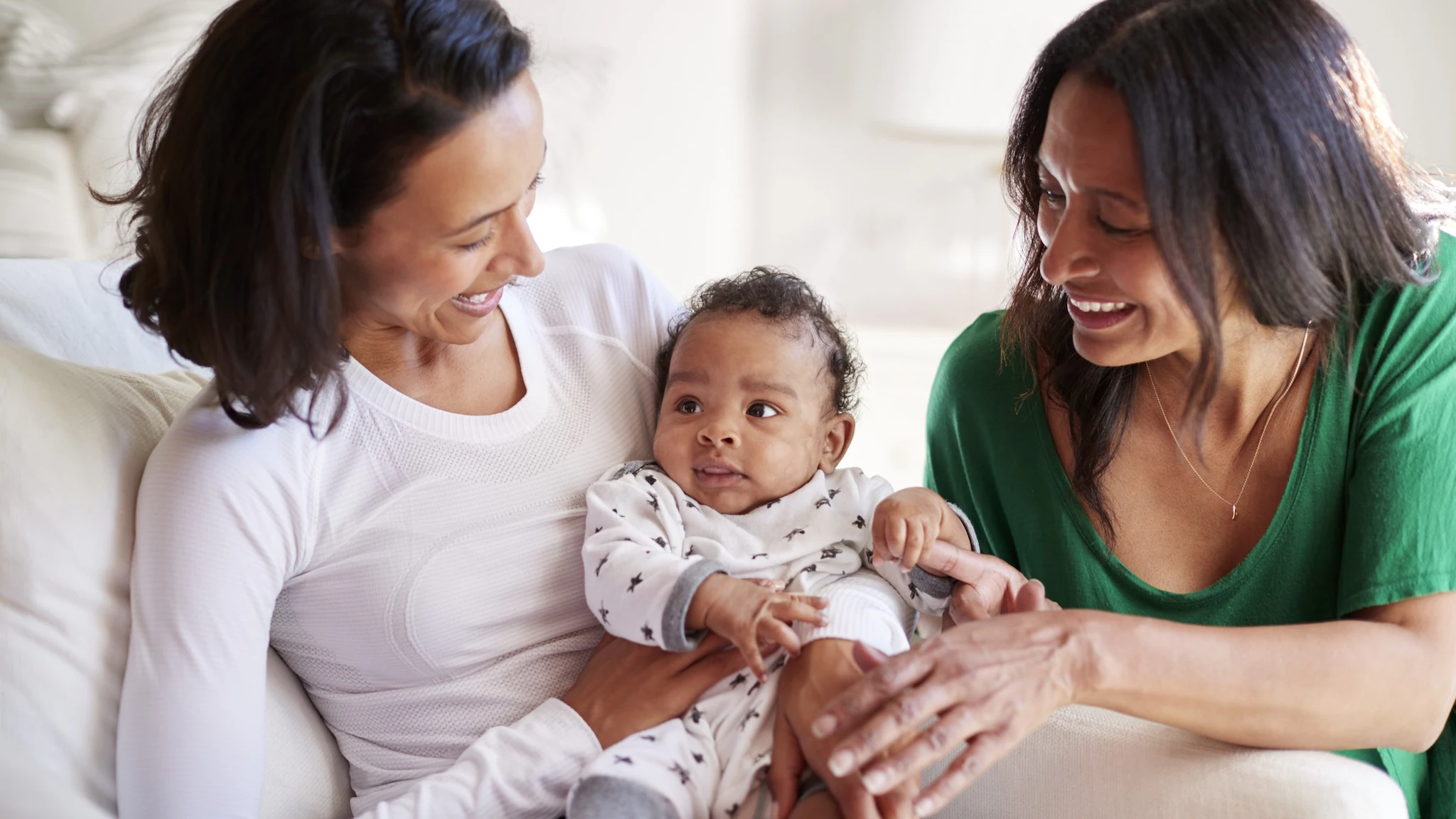 Two women with baby Mother holding an infant while grandmother looks on.