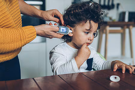 Mother takes child's temperature using a digital thermometer.