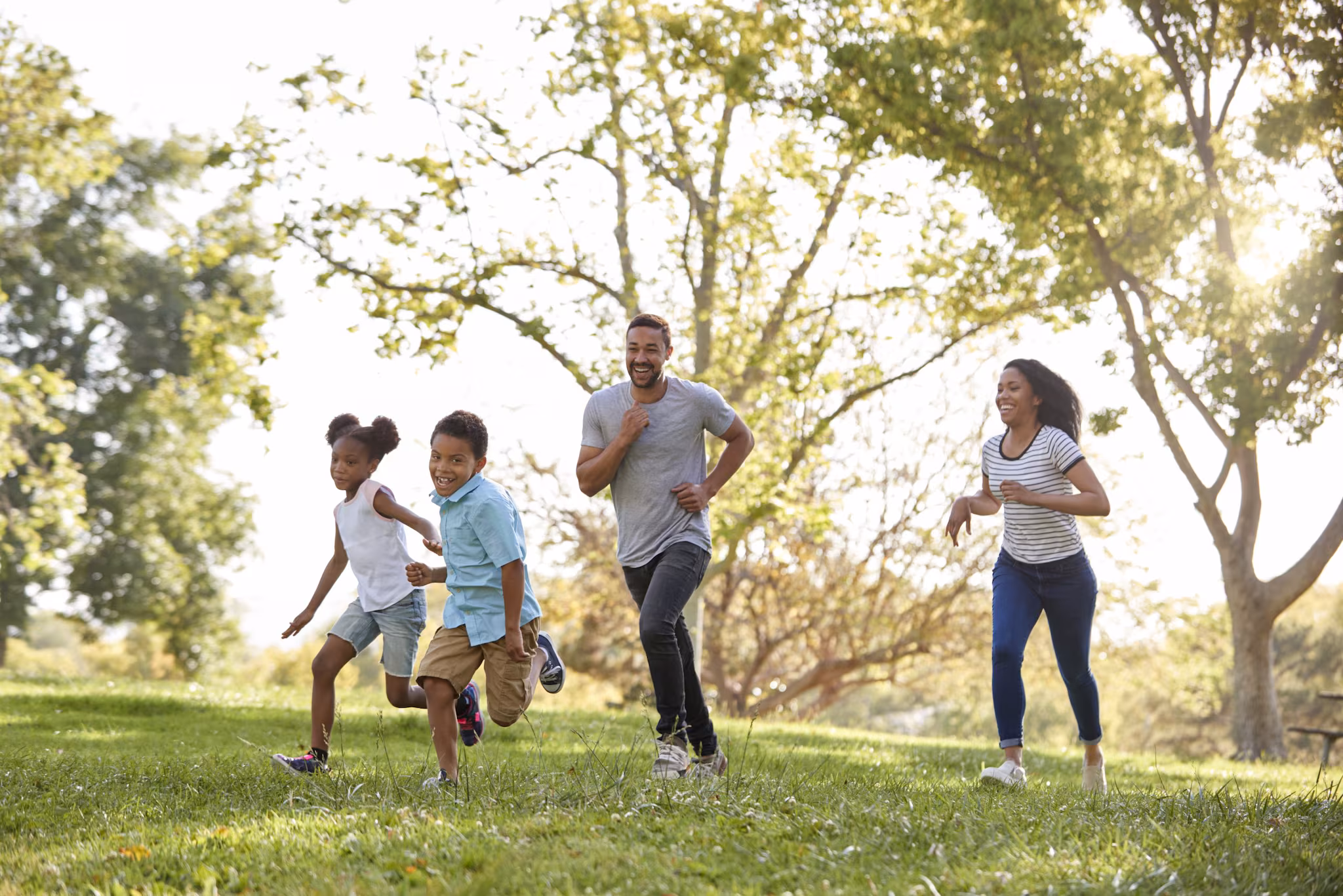 Family running and playing together outdoors Family of two children and two adults run and play together outdoors.
