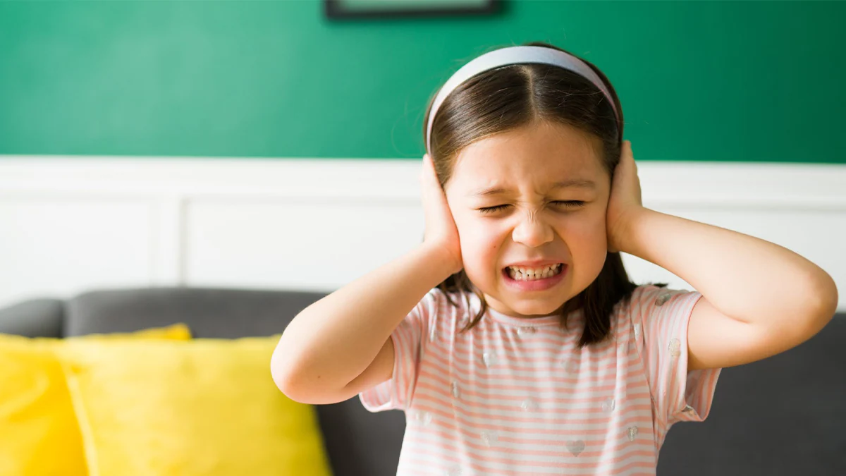 child covering her ears due to loud sounds Young girl covering her ears because of loud sounds