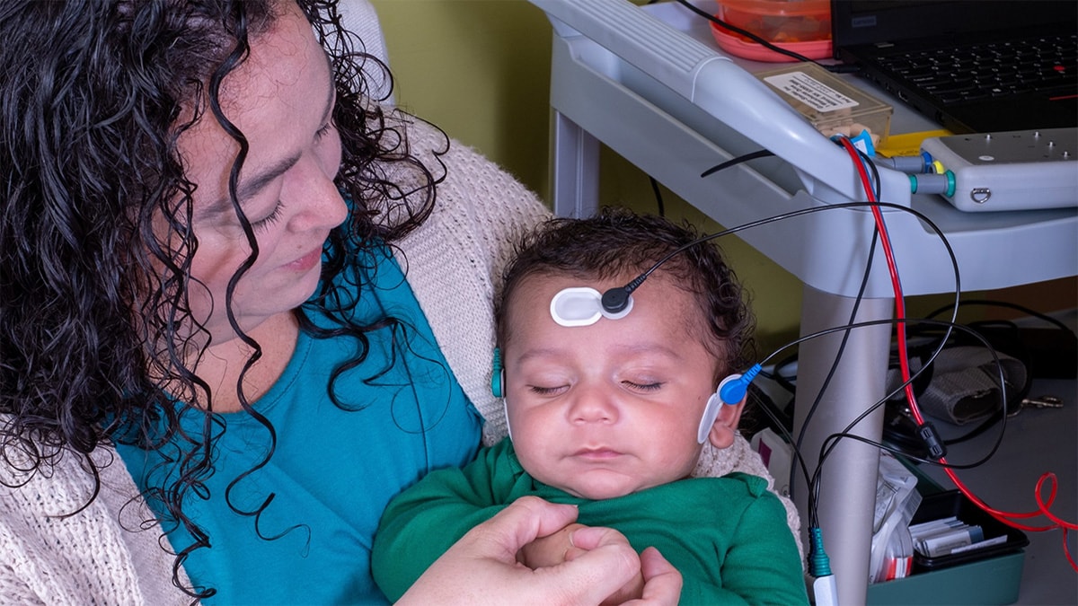 EHDI Program Mom holding sleeping baby during hearing screening