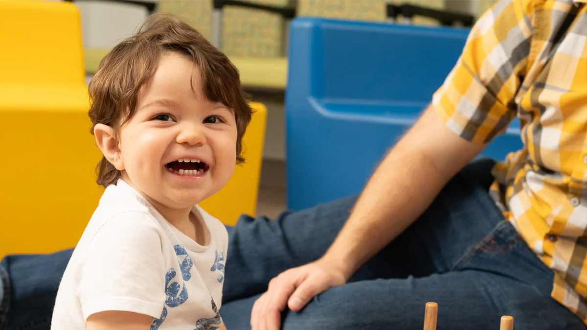 child sitting on ground smiling next to his dad child sitting on ground smiling next to his dad