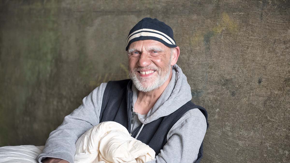 Hepatitis and People Experiencing Homelessness Person experiencing homelessness susceptible to viral hepatitis sits against a concrete wall with a blanket